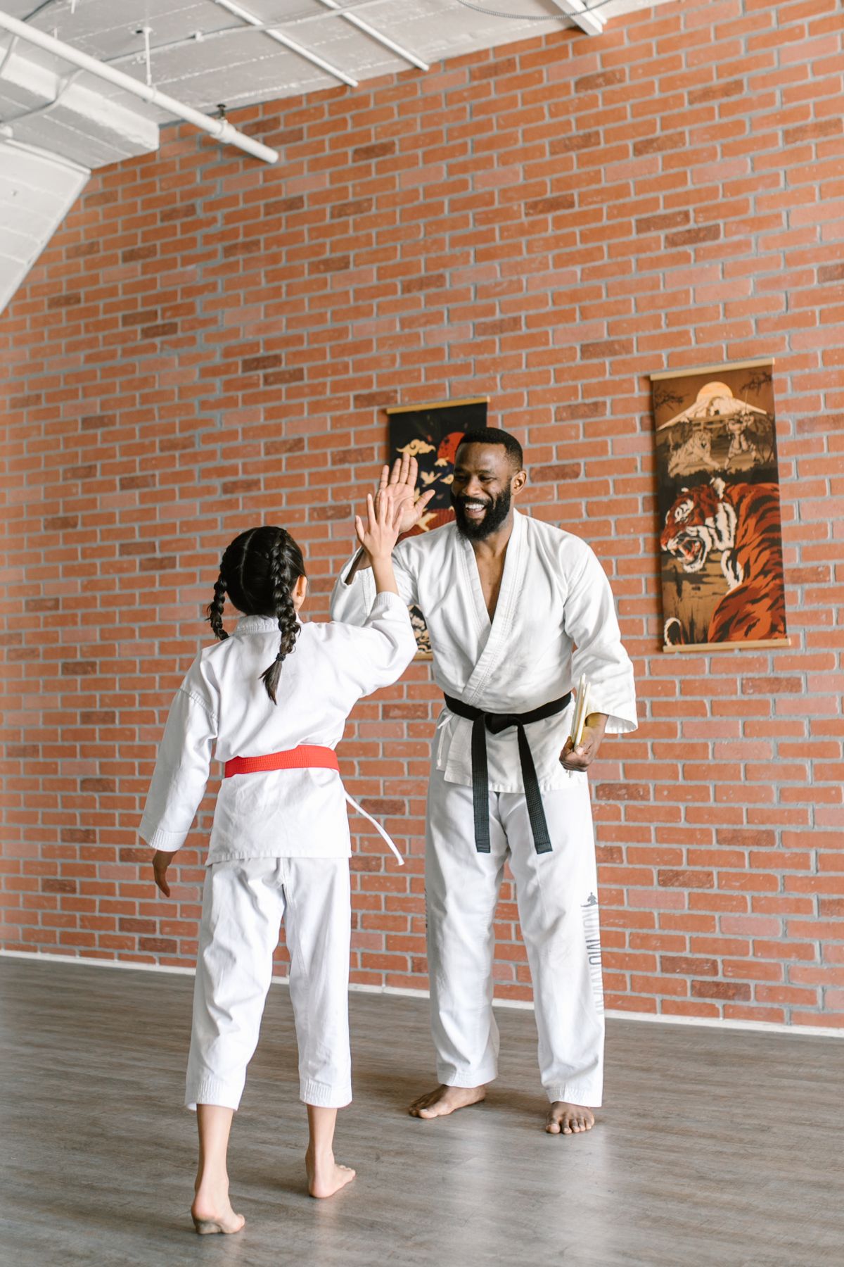 Instructor in a gi high-fiving a young student after class in the dojo