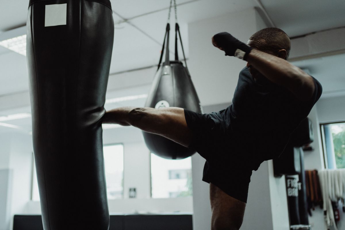 Athlete throwing a roundhouse kick into a heavy bag, shot from a low angle