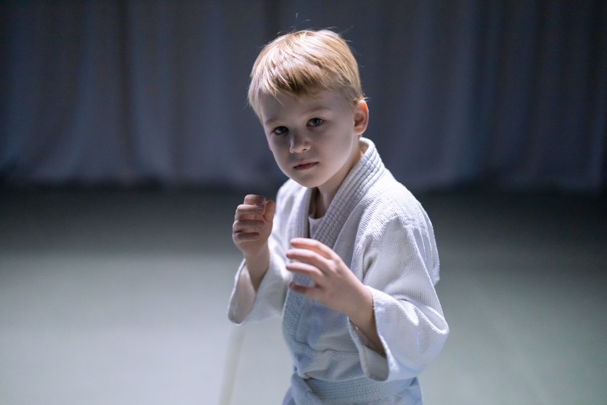 Young boy in a white gi holding a focused fighting stance on the mat